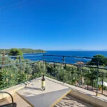A panoramic Aegean Sea view from a private iron-railed balcony with wine, showcasing prime Skiathos studios with sea view.